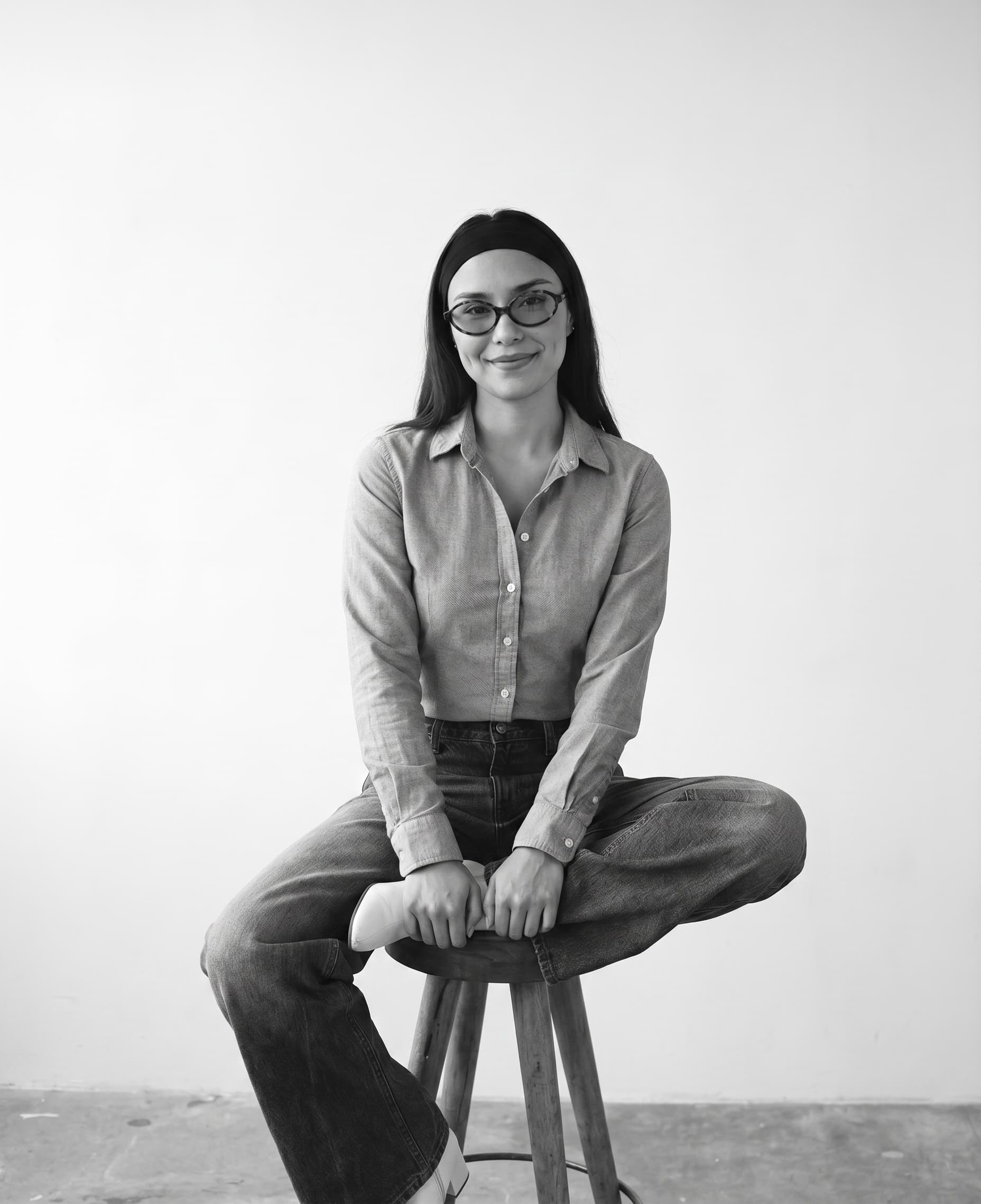 Retrato en blanco y negro de Mariella, diseñadora gráfica, web y fotógrafa de Biianchi Estudio en Costa Rica, sentada sobre un banco de madera